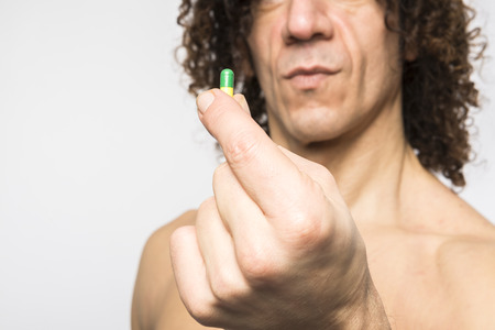Cropped shot of bare chested mediterranean man holding colourful pillの写真素材