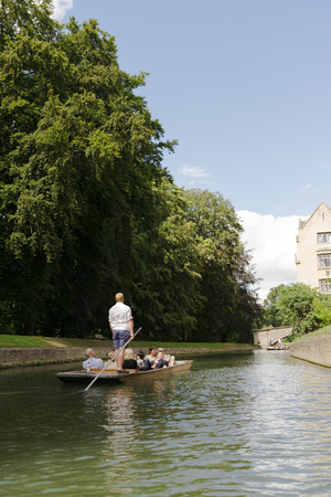CAMBRIDGE, UK - AUGUST 18: Professional punter in busy River Cam with tree lined bank to one side and bridge in the far horizon. August 18, 2013 in Cambridge.のeditorial素材