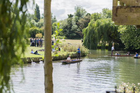 CAMBRIDGE, UK - AUGUST 18: Tourist punters in gondolas in River Cam with park full of trees in the background. August 18, 2013 in Cambridge.のeditorial素材