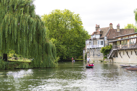 CAMBRIDGE, UK - AUGUST 18: Tourist punters in gondolas in River Cam with park full of trees in the...
