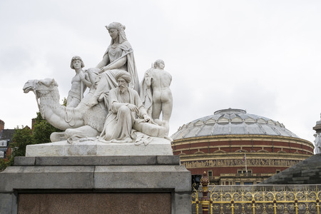 LONDON, UK - SEPTEMBER 14: Detail of one of the four main statues in each corner of the Albert Memorial in Kensington Gardens, with Royal Albert Hall in the background. September 14, 2013 in London.のeditorial素材