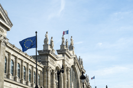 Detail of the Gare du Nord facade with European Union flag in the foreground and French flag in the background.のeditorial素材