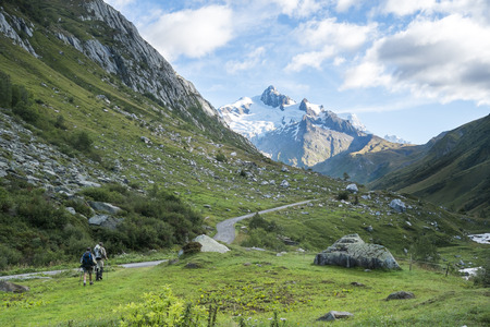 LES CHAPIEUX, FRANCE - AUGUST 27: Hikers walking with Glacier Needles in the background. The region is a stage at the Mont Blanc tour, which crosses three countries. August 27, 2014 in Les Chapieux.のeditorial素材