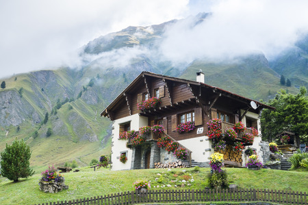 FERRET, SWITZERLAND - AUGUST 30: Beautiful chalet decorated with flowers and with mountains in the background. The village is a stage of the Mont Blanc tour. August 30, 2014 in Ferret.のeditorial素材