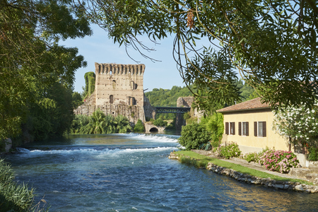 BORGHETTO, ITALY - JULY 11: Ruin of tower at Visconteo bridge, framed by vegetation and coasted by river Mincio. July 11, 2015 in Borghetto.のeditorial素材