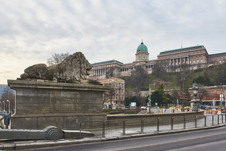 Lion statue over Szechenyi Chain Bridge with Buda Castle in the background. February 02, 2016 in Budapest, Hungary.のeditorial素材