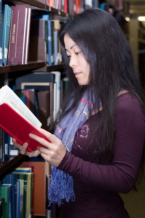 A young female student reading in the library.の写真素材