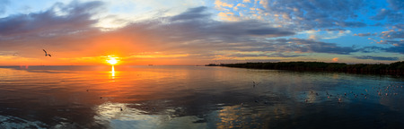 Panorama Tranquil scene cloudy sea sunset with seagulls flying at sunset at Bang Poo Recreational Retreat, Samut Prakan, Thailand.の写真素材