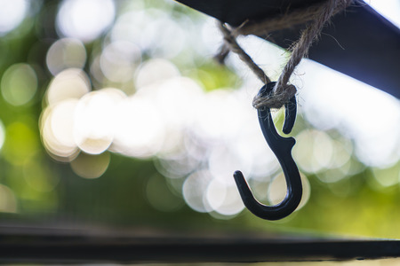 empty hook hangs by a hemp rope with green bokeh background.の写真素材