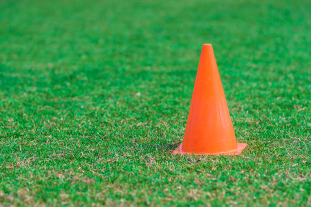 Orange cone standing on a green grass soccer field with copy space.の写真素材