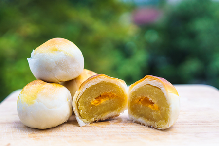 Chinese pastry puff, Beans cake with salted egg yolk lay on wood with green nature bokeh background.の写真素材