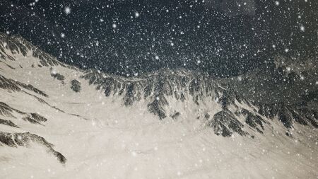 Heavy snowing, focused on the snowflakes, mountains in the backgroundの写真素材