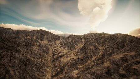 the sun's rays against the backdrop of the mountains and the lava-rocky wet shore in the foregroundの写真素材