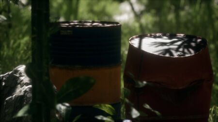 Rusty barrels in green forest illustrates the pollution of environment by oil spills