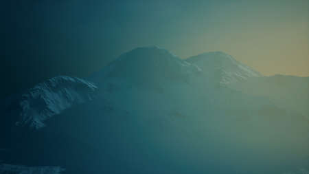 Dramatic dark rocky mountain with patches of snow in stormの写真素材