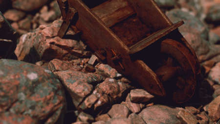abandoned wooden mine wheelbarrow on rocksの写真素材