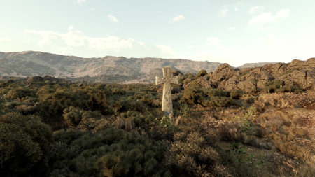 A cemetery cross standing tall in a serene field with majestic mountains in the backgroundの写真素材