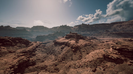 The rocky terrain stretches across the horizon, illuminated by the midday sun. Cloud formations drift above, enhancing the rugged beauty of this natural environment.の写真素材