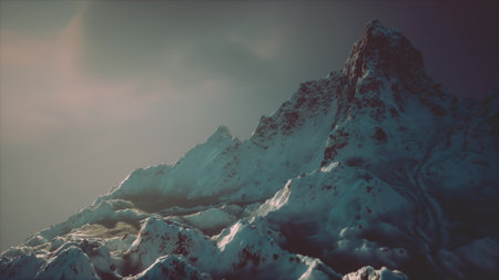 The snow capped peaks reflect the fading light of dusk, creating a stunning contrast against the darkening sky. Rugged terrain showcases natures grandeur in winters embrace.の写真素材