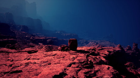 Twilight casts deep hues over the rugged terrain of a vast canyon with silhouetted cliffs in the distance.の写真素材