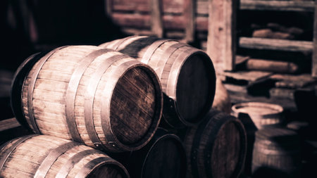 A collection of wooden barrels stacked closely together inside an aged warehouse, illuminated by...