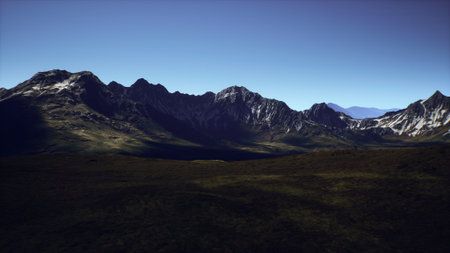 A stunning view of a rugged mountain range basking in sunlight. The clear blue sky contrasts...