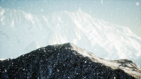 Snow blankets rugged mountains as a flurry of frost swirls through the air. This serene winter scene captures the beauty of nature at its quietest.の写真素材