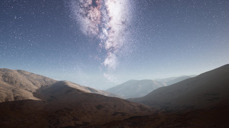 Above the rugged terrain of the mountains, the Milky Way shines brightly against the night sky.の写真素材