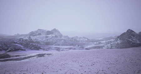 A vast winter landscape shows a blanket of snow over rocky terrain. Low visibility and a gray sky create a serene and cold atmosphere, highlighting natures quiet beauty.の写真素材