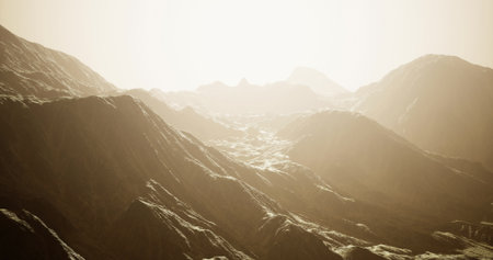 Tall mountains stretch across the horizon, illuminated by the warm glow of the sun rising early in the morning. The rugged terrain creates a tranquil atmosphere, inviting exploration.の写真素材