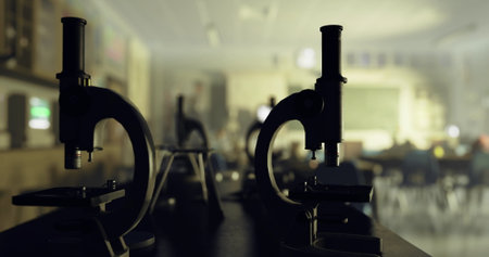 Several microscopes are positioned on a table, focusing on a classroom filled with students engaging in a science lesson, creating a lively educational atmosphere.の写真素材