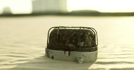 A weathered metal object rests on a shore of fine sand, illuminated by the golden light of the setting sun. The surface shows signs of wear, blending with the tranquil surroundings.の写真素材