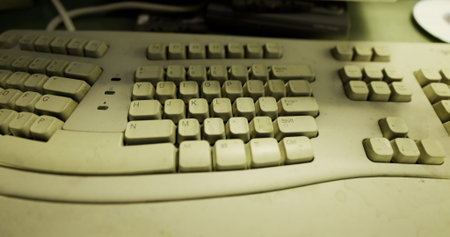 Dust accumulates on a once vibrant computer keyboard, capturing a moment of neglect in a cluttered workspace. Memories of typing and communication linger in the air.の写真素材