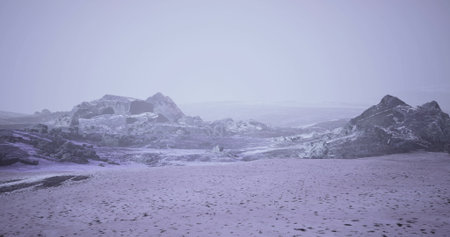 A serene, cold landscape unfolds under a soft twilight sky where frost covered rocks rise majestically. Delicate snow blankets the ground, creating a tranquil winter atmosphere.の写真素材