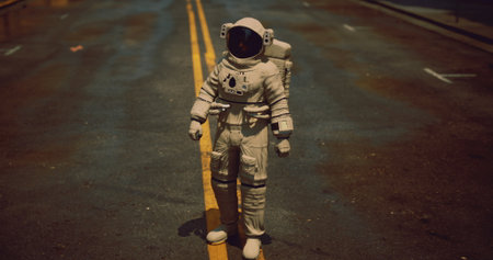 An astronaut stands confidently on a deserted city street, the asphalt glistening after rain. This unexpected presence evokes a sense of wonder in an ordinary urban setting.の写真素材