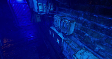 Dimly lit alleyway features aged electrical meters and equipment surrounded by brick walls. Blue light casts an eerie glow, enhancing the urban decay atmosphere at night.の写真素材