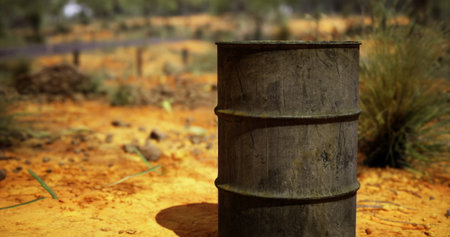 A rusty, weathered barrel stands alone in a parched, rugged terrain. Surrounding grasses dry under the afternoon sun, hinting at a stark wilderness untouched by time.の写真素材