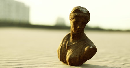 A serene bronze sculpture stands on golden sands, gently illuminated by the warm evening light. The...