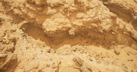 Sunlight illuminates intricate sandstone rock formations in a vast desert. The rugged terrain features various textures and colors, showcasing the natural beauty of the arid environment.の写真素材