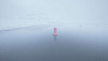 A red metal buoy is seen floating on top of the cold Norwegian sea.の写真素材