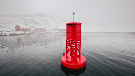 A red metal buoy buoyantly floats on the expansive, cold Norwegian sea.の写真素材