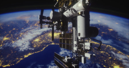 The International Space Station orbits Earth, illuminated by city lights during nighttime. The curve of the planet and visible continents create a stunning view from space.の写真素材