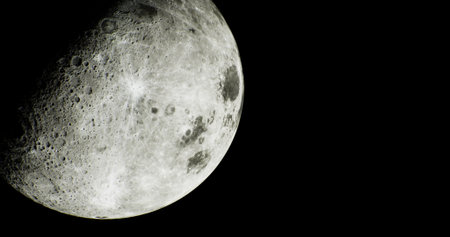 Bright moon casts a soft glow in the night sky, highlighting its textured surface and craters. A clear view allows appreciation of its beauty against the deep darkness.の写真素材