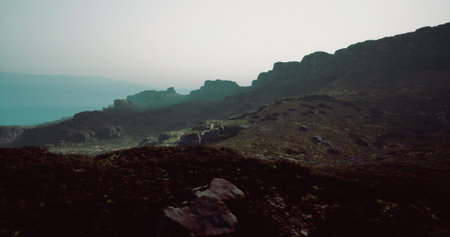 A rocky landscape stretches across the horizon during twilight, with mist covering the distant...