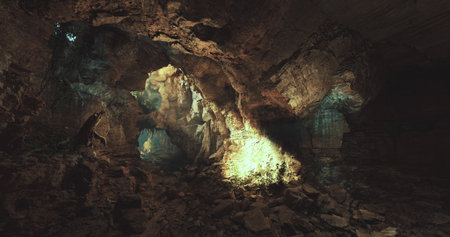 Cavernous space reveals intricate rock formations and glowing light streaming through openings....