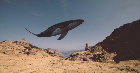 A massive whale floats gracefully above a rugged terrain of rocks and cliffs, showcasing its majestic form against a clear blue sky in a serene mountain environment.の写真素材