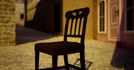 A wooden chair sits alone on a cobblestone street in a quaint village. The warm hues of sunset cast shadows as the day comes to a close. Nearby, a charming building adds to the peaceful ambiance.の写真素材
