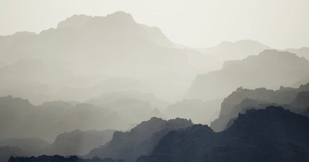Layers of mountains fade into the distance, shrouded in mist during early morning hours. The soft...