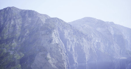 Dramatic mountain range towers over a tranquil lake, reflecting the pristine landscape. The clear...