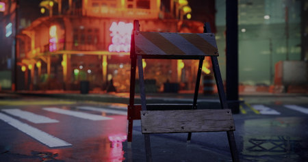 A construction barrier stands on a wet city street, glowing from surrounding neon lights. The...